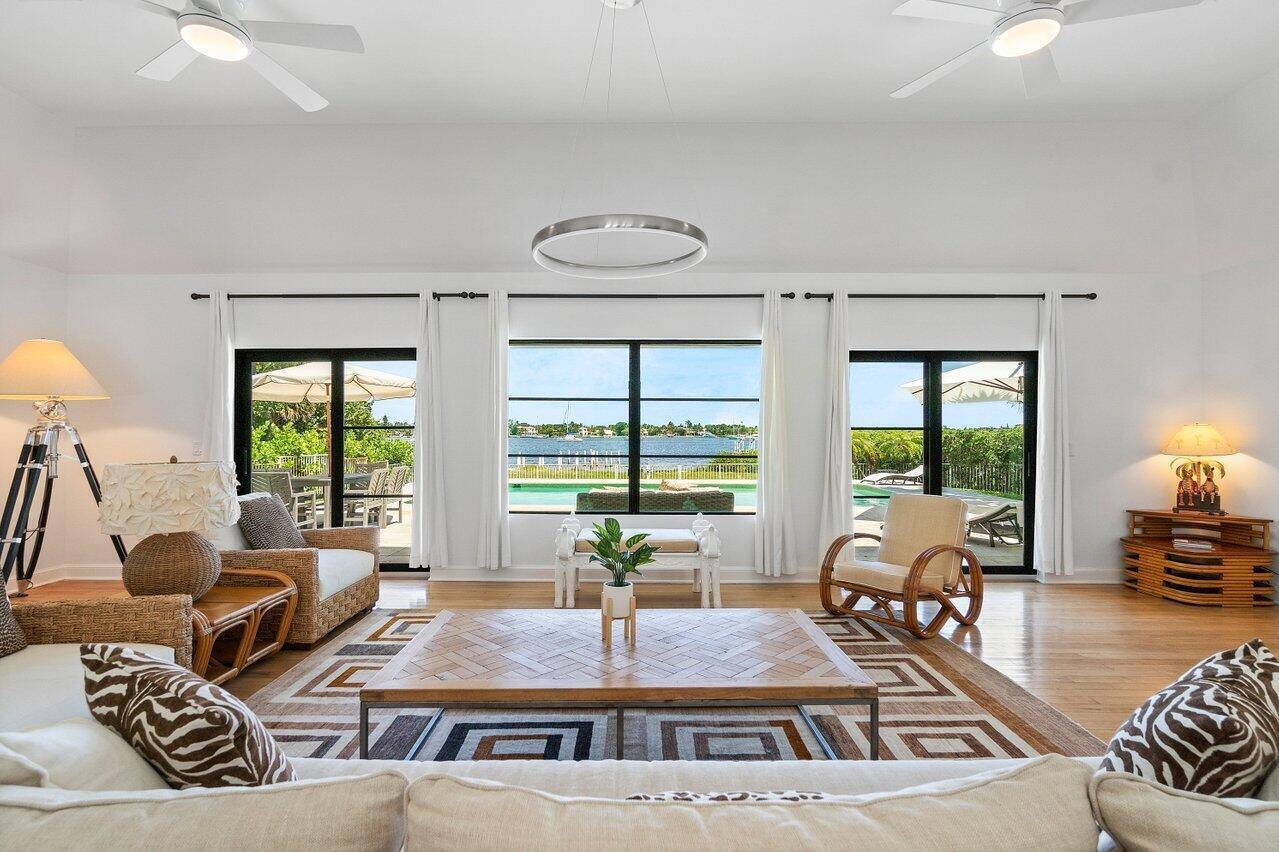 A bright living room features a large wooden coffee table, wicker furniture, and water views — 210 S Lake Drive, Lantana FL 33462, LANTANA, FL
