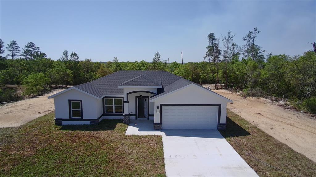 A single-story house with a white exterior, dark trim, and a two-car garage — 13521 SW 106TH STREET, DUNNELLON, FL