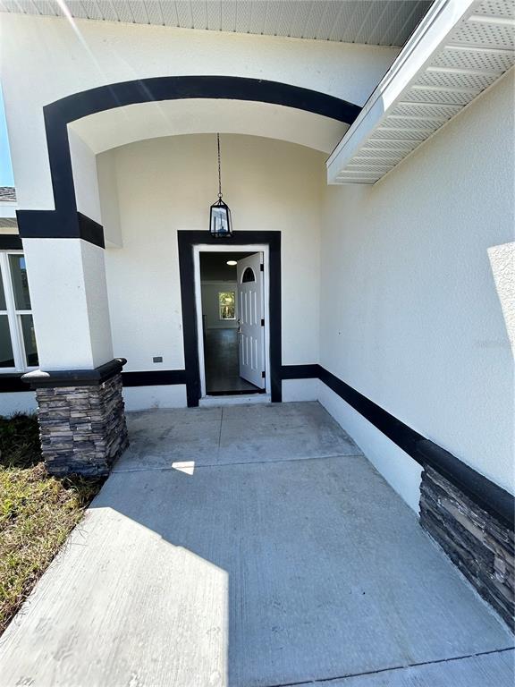 A concrete porch leads to an open front door with black trim and stone accents — 13521 SW 106TH STREET, DUNNELLON, FL