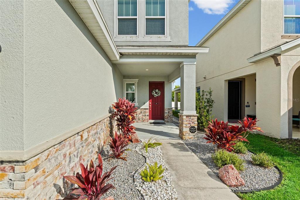 A walkway leads to the red front door of a house with stone accents — 4327 REISSWOOD LOOP, PALMETTO, FL