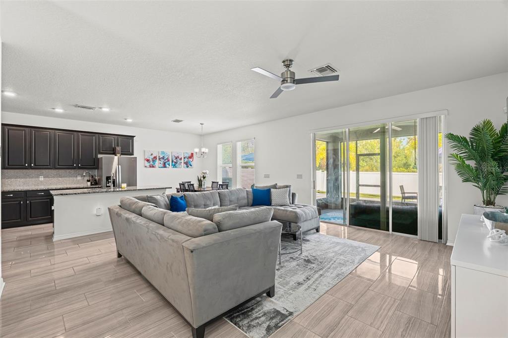 A living room with a grey sectional sofa, tiled floors, and sliding doors to a patio — 4327 REISSWOOD LOOP, PALMETTO, FL