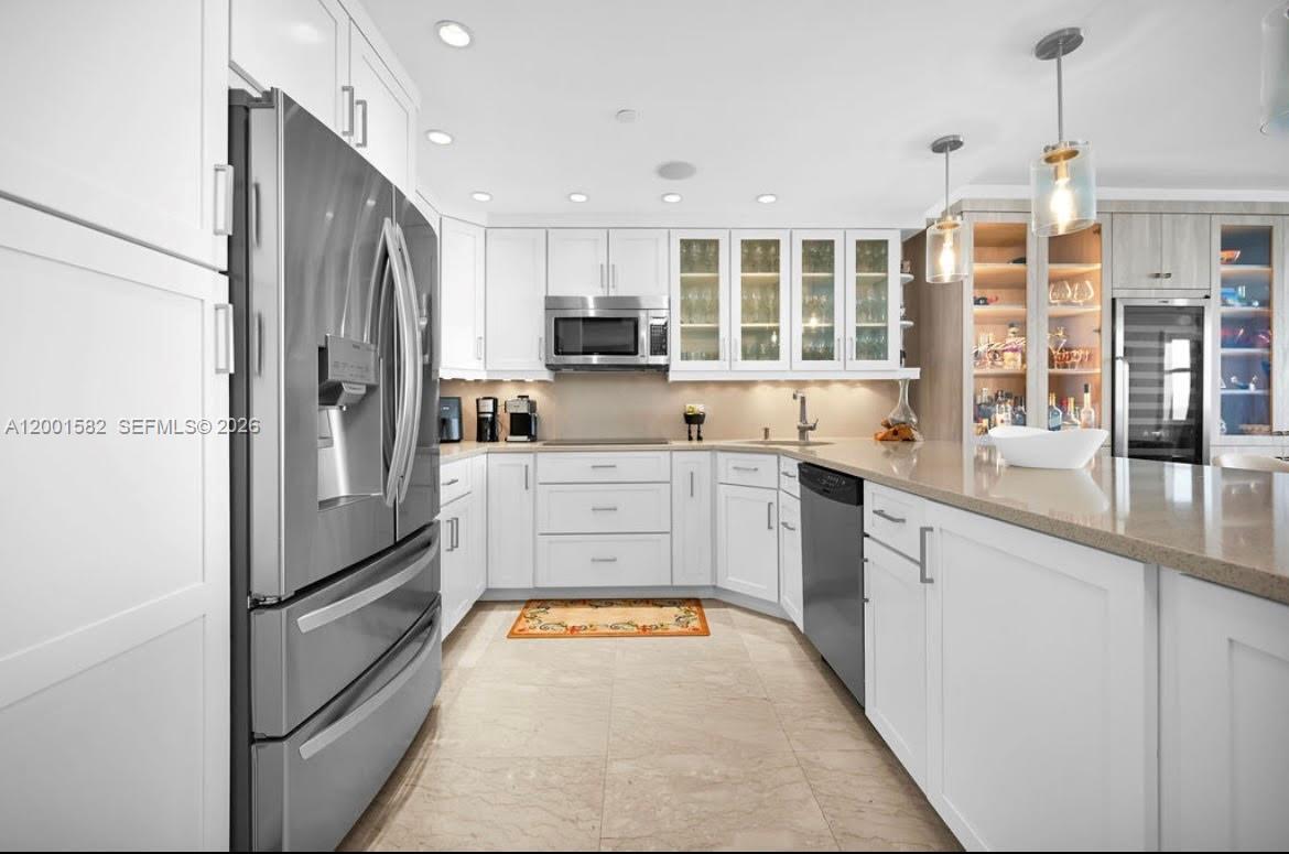 A modern kitchen features white cabinetry, stainless steel appliances, and a large stone-topped island — 5601 Collins Ave # 903, Miami Beach FL 33140, MIAMI BEACH, FL