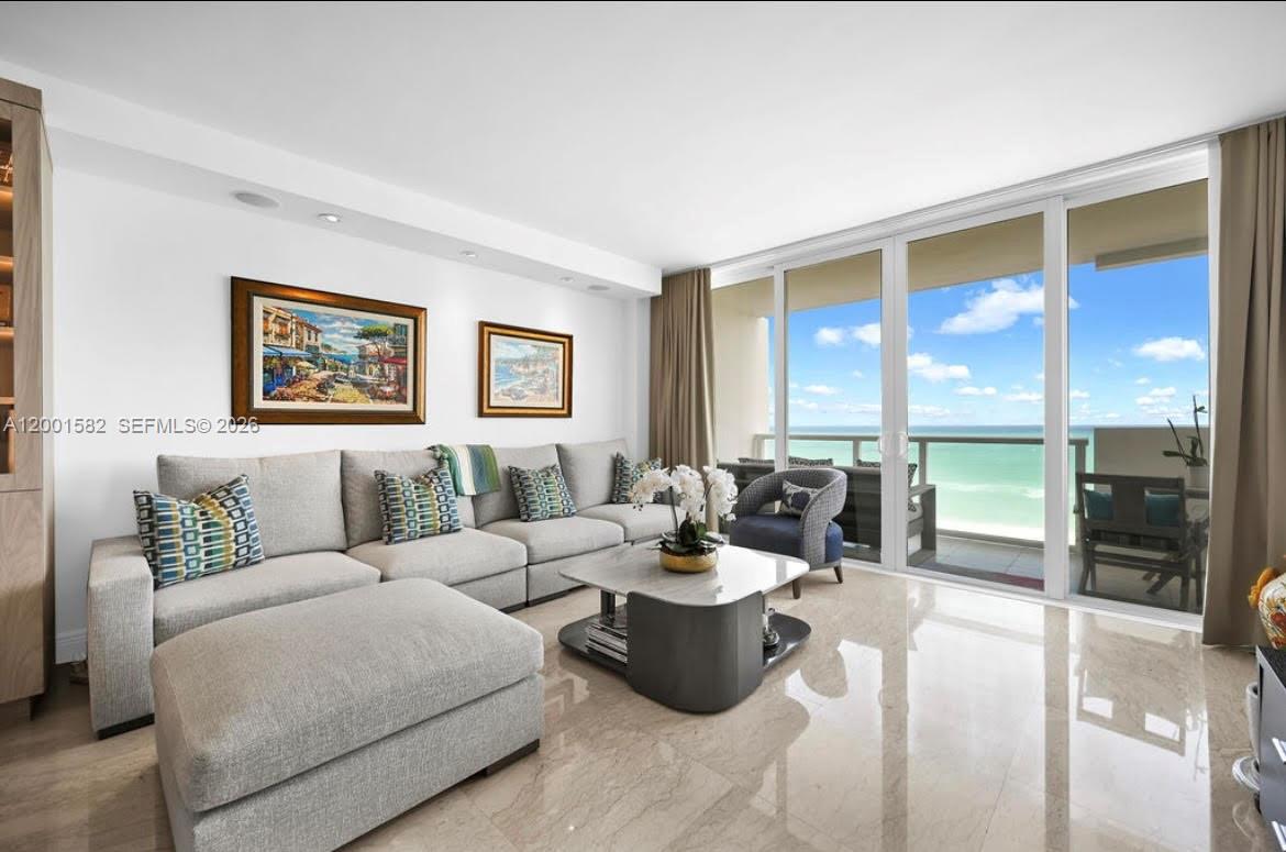 A living room with a sectional sofa, marble floors, and a balcony overlooking the ocean — 5601 Collins Ave # 903, Miami Beach FL 33140, MIAMI BEACH, FL