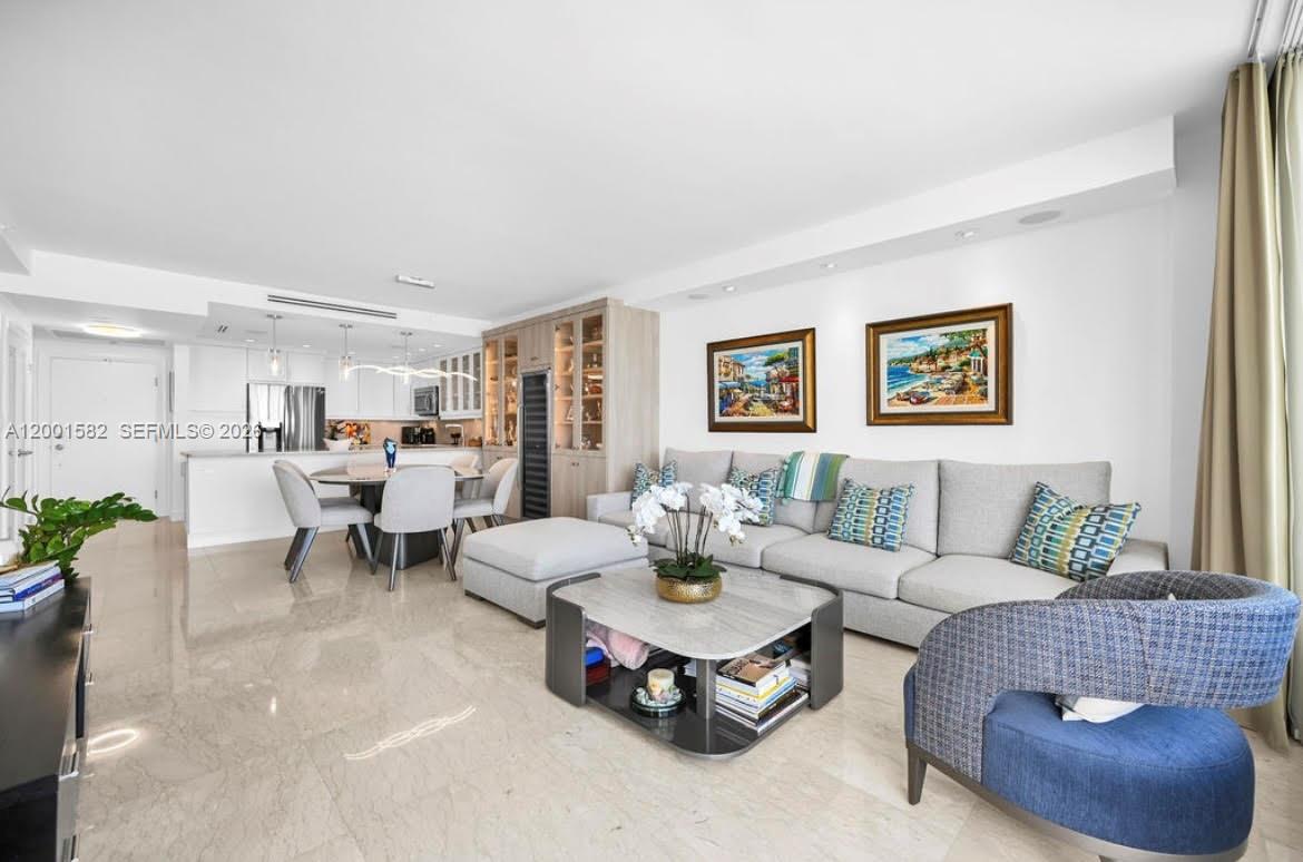A living room features a grey sectional sofa, a coffee table, and an open kitchen — 5601 Collins Ave # 903, Miami Beach FL 33140, MIAMI BEACH, FL