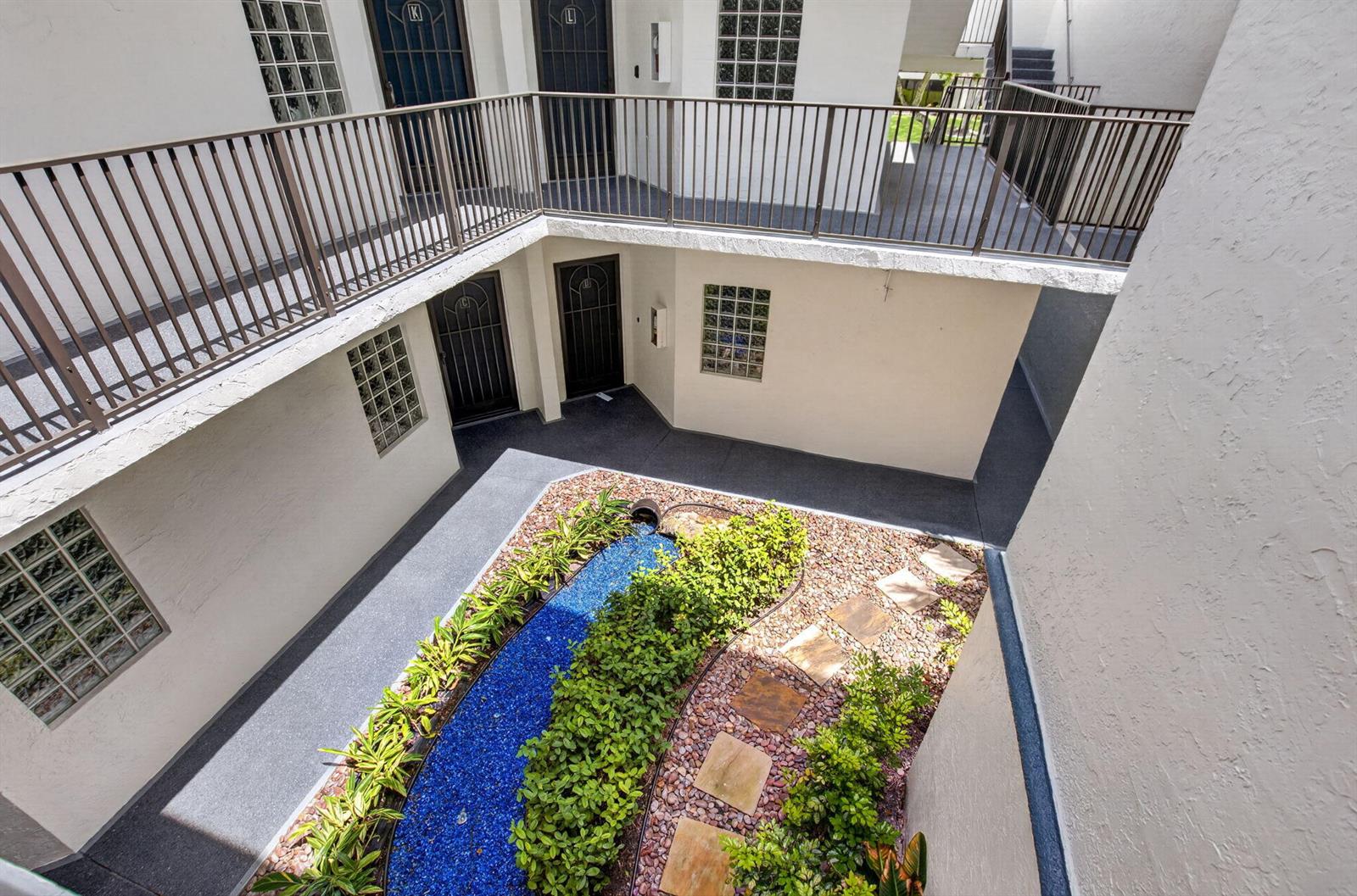 An elevated view of an apartment complex courtyard featuring a blue glass-filled water feature — 5153 Floria Drive # J, Boynton Beach FL 33437, BOYNTON BEACH, FL