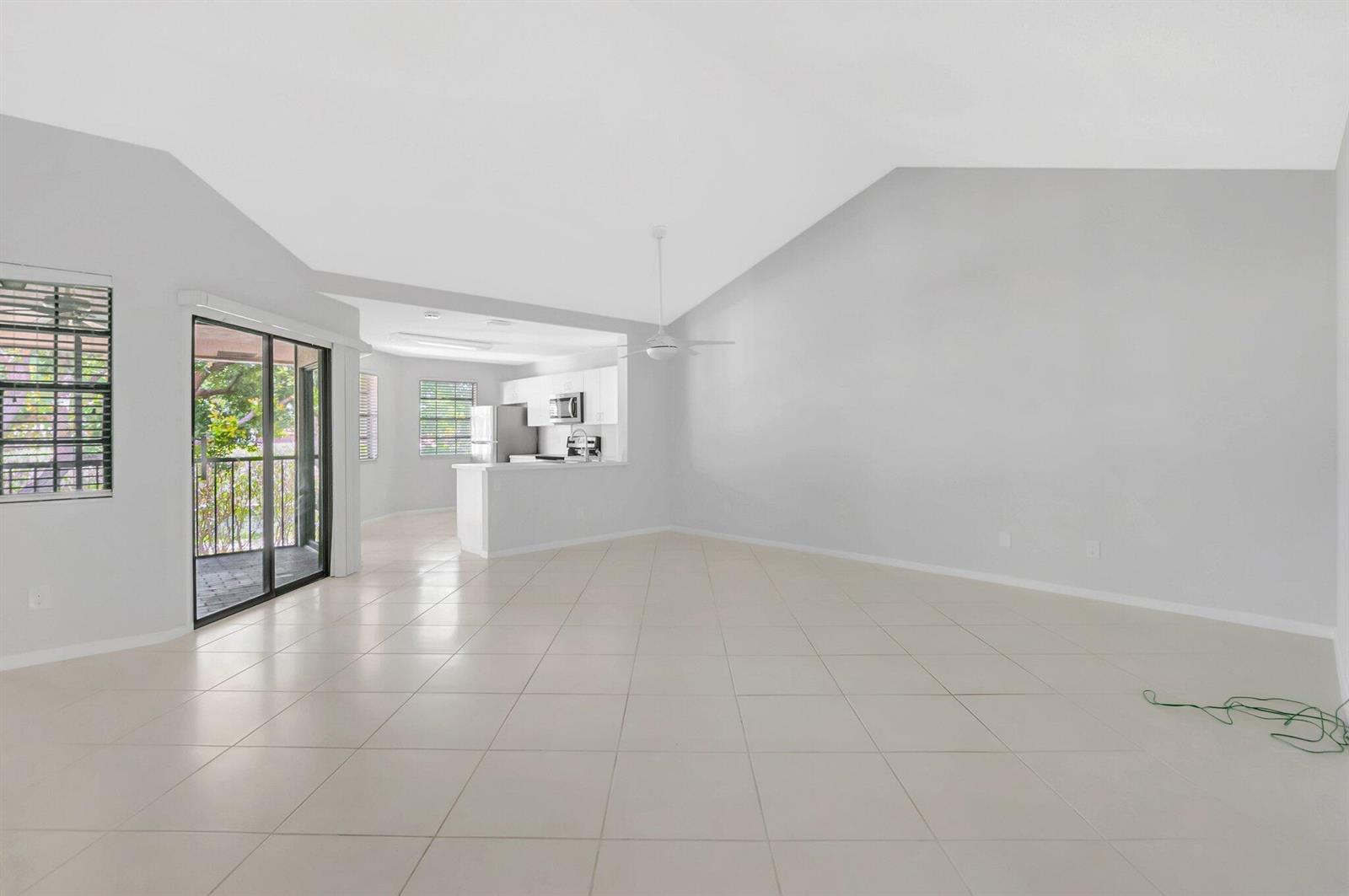 An open-concept living area features light tile flooring, vaulted ceilings, and an adjacent kitchen — 6658 Montego Bay Boulevard # D, Boca Raton FL 33433, BOCA RATON, FL