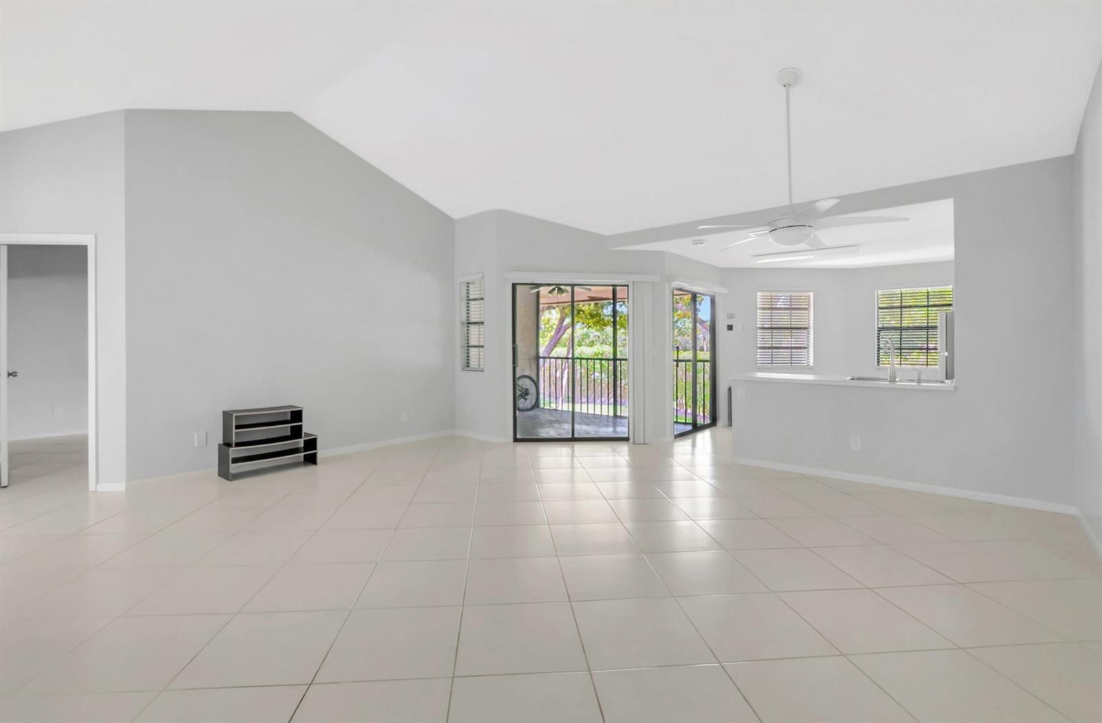 An open-concept living area features vaulted ceilings, light tile flooring, and sliding glass patio doors — 6658 Montego Bay Boulevard # D, Boca Raton FL 33433, BOCA RATON, FL