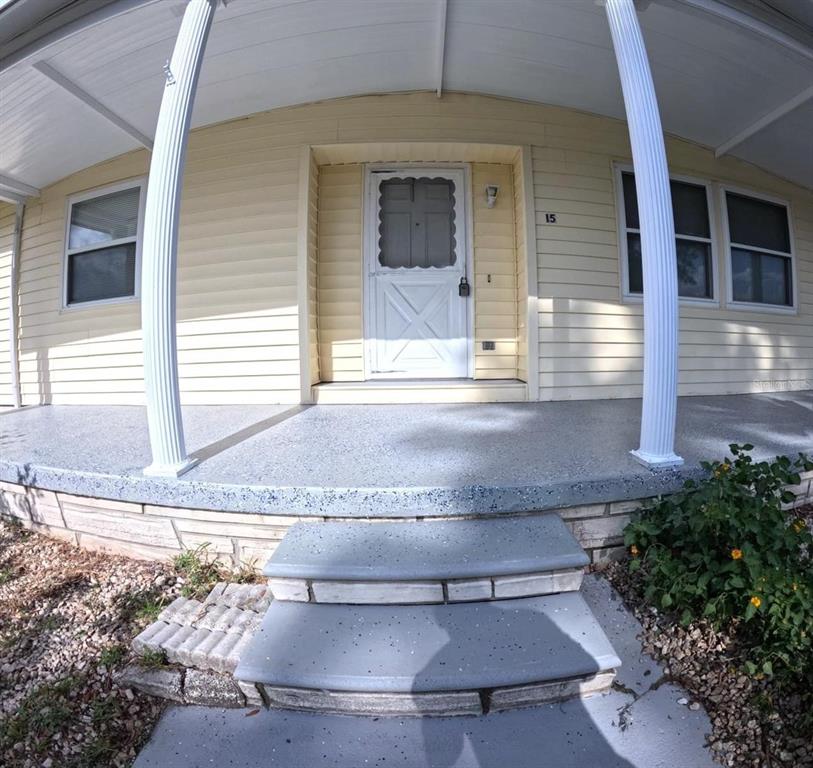 A front porch with a gray speckled concrete floor and two steps leading to a door — 15 NE 63RD COURT, OCALA, FL