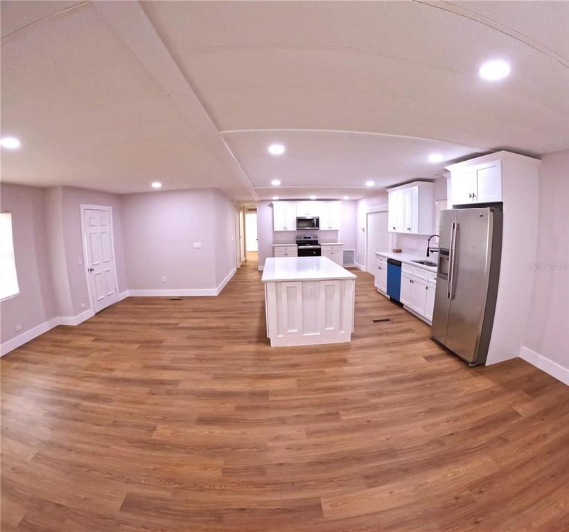 A kitchen with white cabinets, a central island, and stainless steel appliances on wood flooring — 15 NE 63RD COURT, OCALA, FL