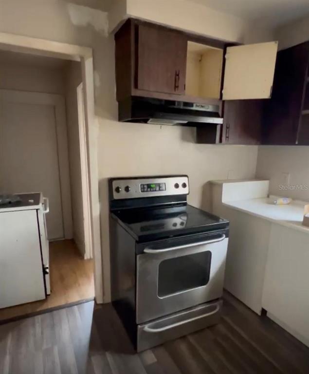 A kitchen features a stainless steel electric range, dark wood cabinets, and white countertops — 8213 N 17TH STREET, TAMPA, FL
