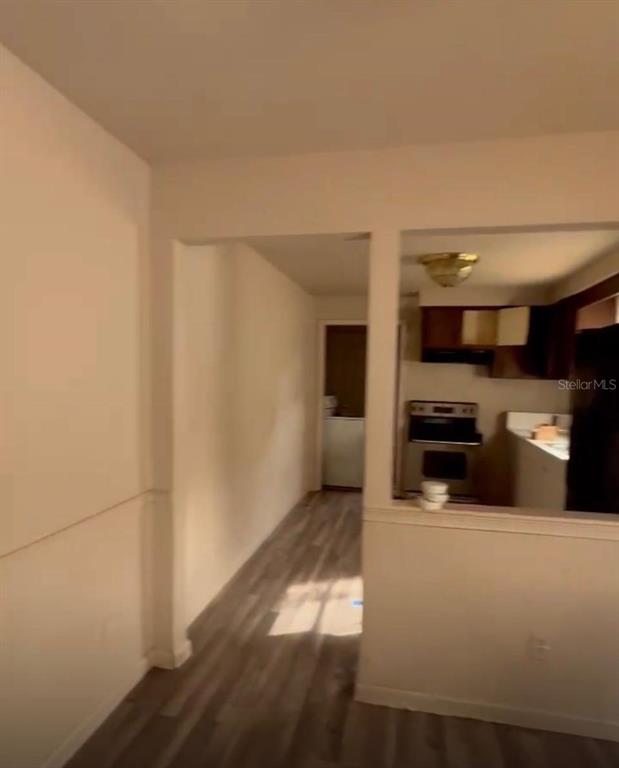A view from a room looking into a kitchen with wood-look flooring and white walls — 8213 N 17TH STREET, TAMPA, FL
