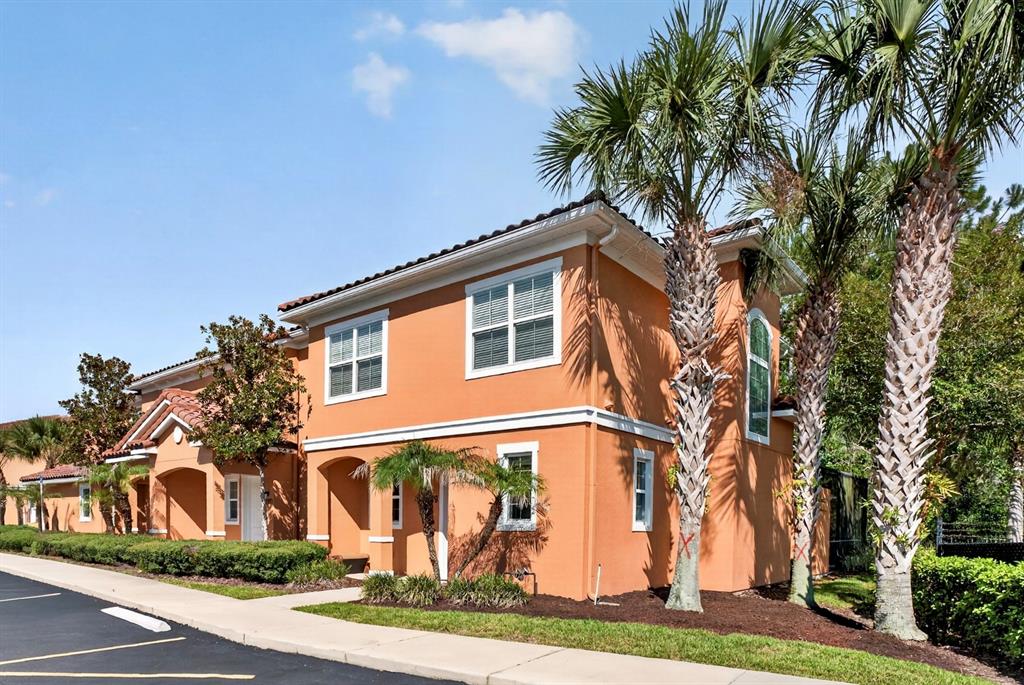A two-story orange stucco building with a tiled roof and palm trees in the foreground — 2679 CORVETTE LANE, KISSIMMEE, FL