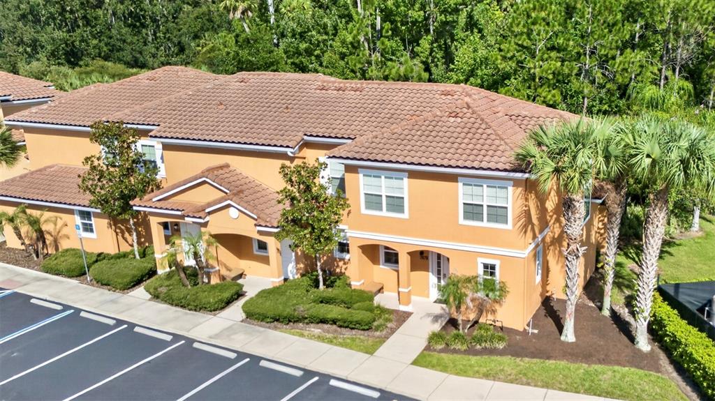 An aerial view of a two-story tan stucco townhouse with a tiled roof and landscaping — 2679 CORVETTE LANE, KISSIMMEE, FL