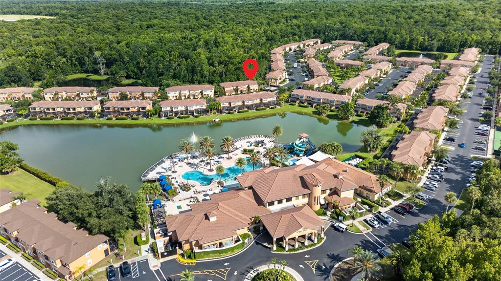 An aerial view shows a residential complex with a central pool, lake, and clubhouse — 2679 CORVETTE LANE, KISSIMMEE, FL