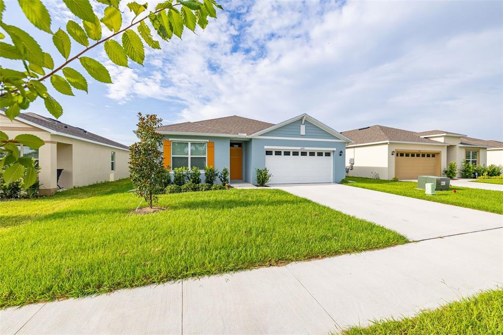 A light blue single-story house with a white garage door and a concrete driveway — 1078 CLAY BOULEVARD, TAVARES, FL