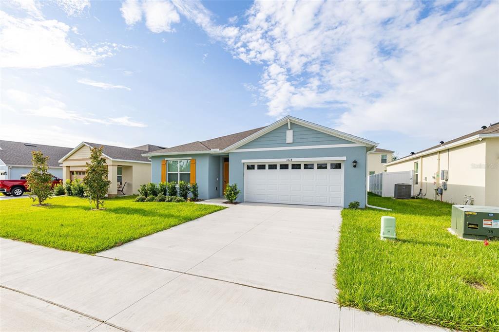 A light blue single-story house with a two-car garage and a green lawn — 1078 CLAY BOULEVARD, TAVARES, FL