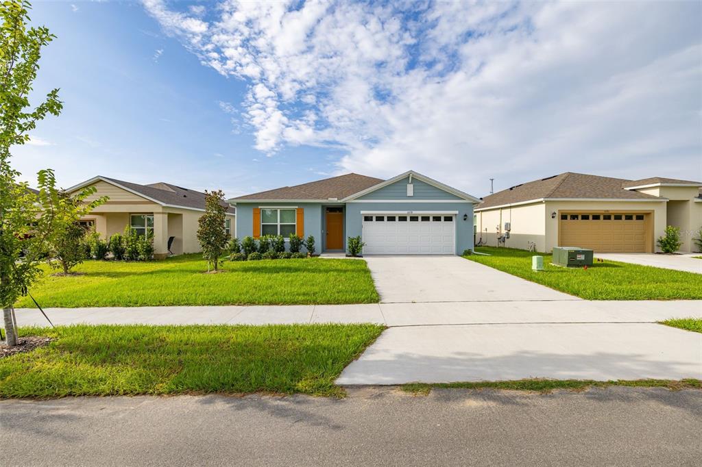 A blue single-story house with a white garage door and a concrete driveway — 1078 CLAY BOULEVARD, TAVARES, FL