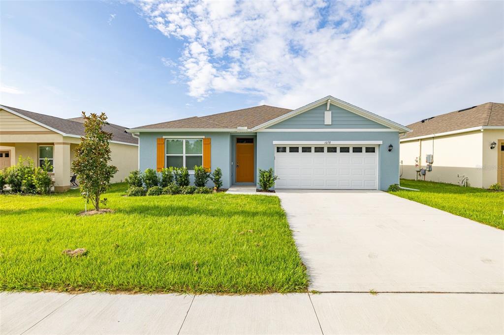 A light blue single-story house with a white garage door and an orange front door — 1078 CLAY BOULEVARD, TAVARES, FL