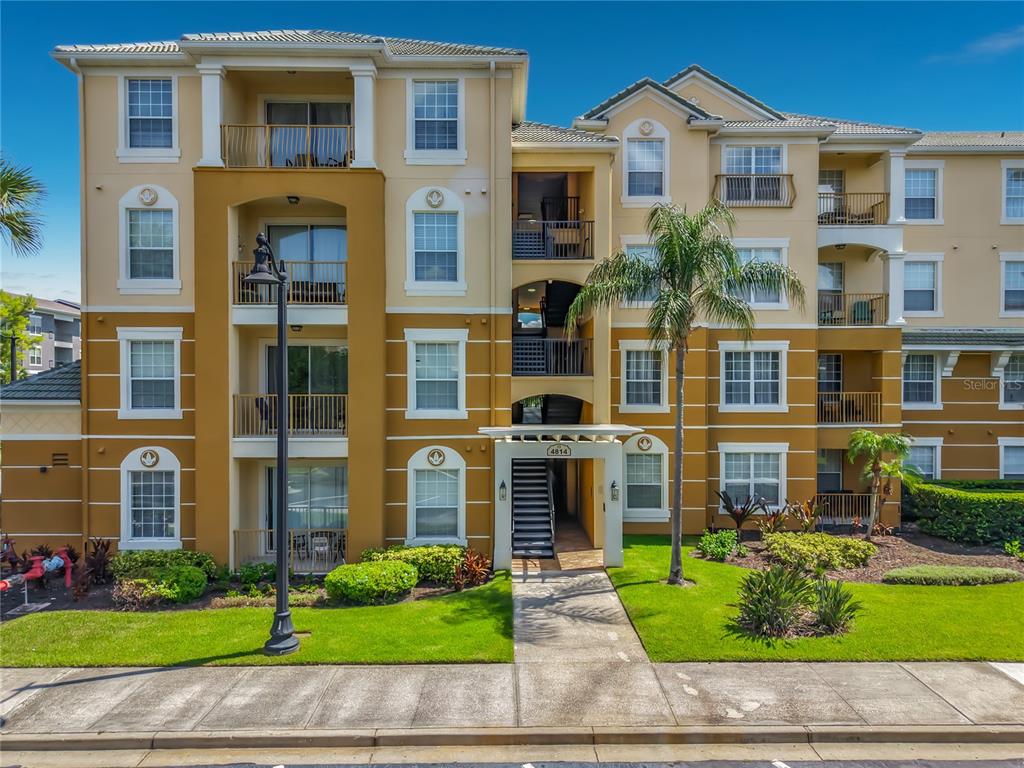 Exterior view of a multi-story apartment building with balconies, tan stucco walls, and landscaping — 4814 CAYVIEW AVENUE UNIT 10213, ORLANDO, FL