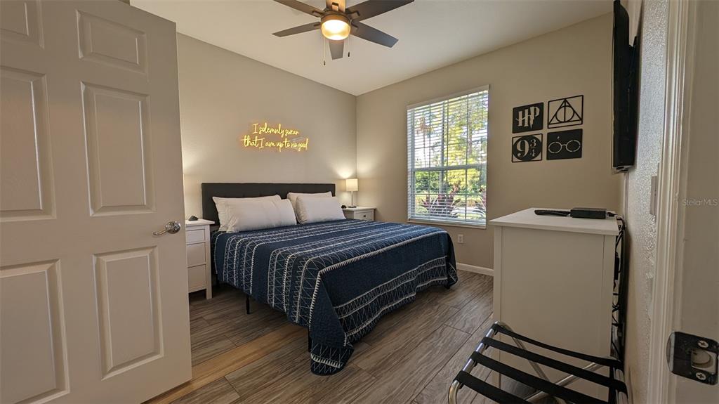 A bedroom features a bed with a blue patterned quilt, wood-look flooring, and Harry Potter-themed decor — 4814 CAYVIEW AVENUE UNIT 10213, ORLANDO, FL