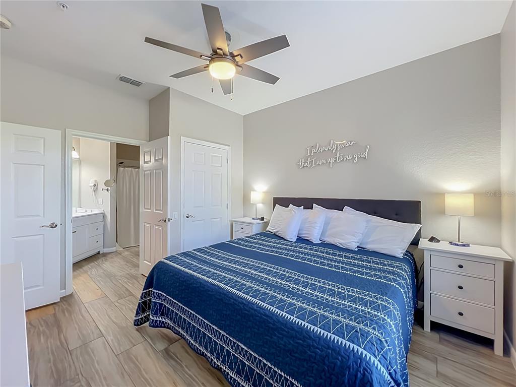 A bedroom features a blue patterned quilt, a ceiling fan, and an attached bathroom — 4814 CAYVIEW AVENUE UNIT 10213, ORLANDO, FL