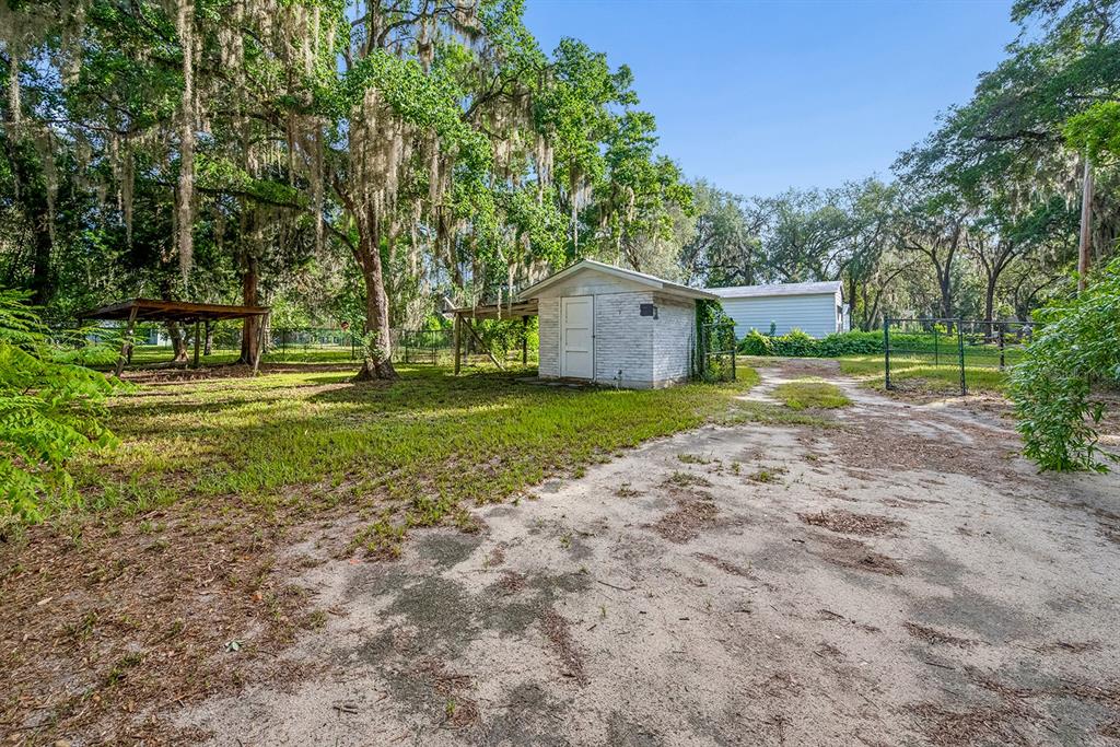 A brick house features a covered front porch with white columns and a metal roof — 7908 LAKE GENEVA LANE, KEYSTONE HEIGHTS, FL