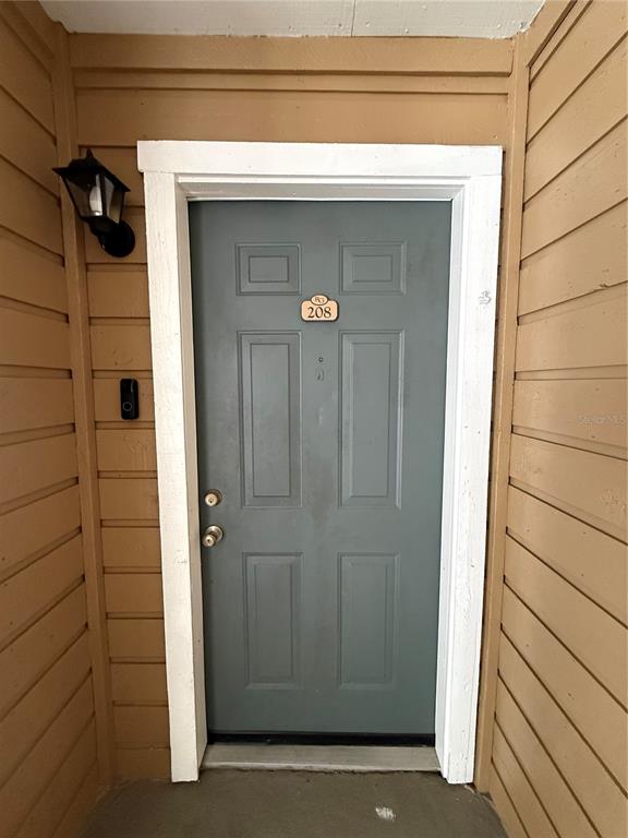 A gray front door with the number 208 is set within tan horizontal siding — 4367 THORNBRIAR LANE UNIT P208, ORLANDO, FL