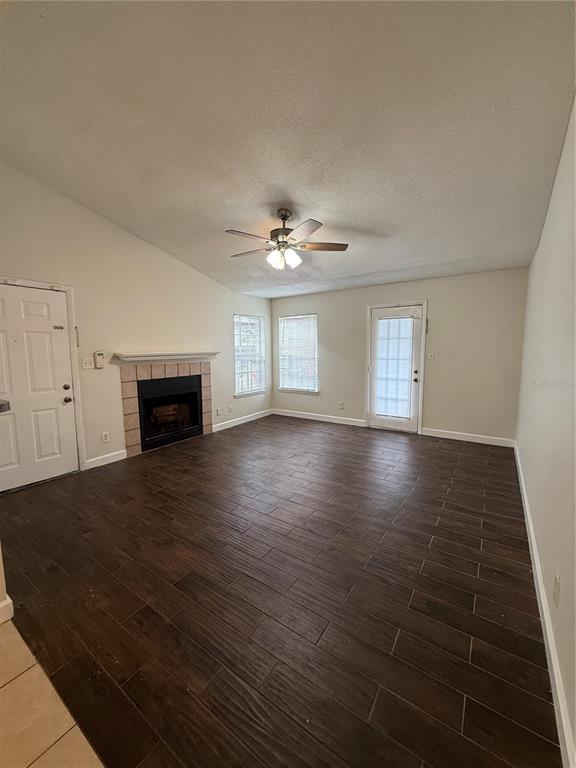 A living room features dark wood-look tile floors, a fireplace, and a ceiling fan — 4367 THORNBRIAR LANE UNIT P208, ORLANDO, FL