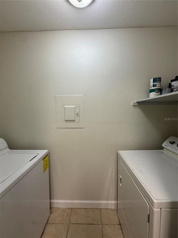 A laundry room features a washer, a dryer, a wall-mounted electrical panel, and a shelf — 4367 THORNBRIAR LANE UNIT P208, ORLANDO, FL
