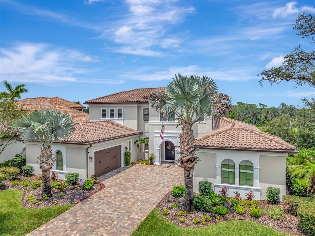 A two-story house with a tile roof, paved driveway, and palm trees in the front yard — 14922 FISHHAWK PRESERVE DRIVE, LITHIA, FL