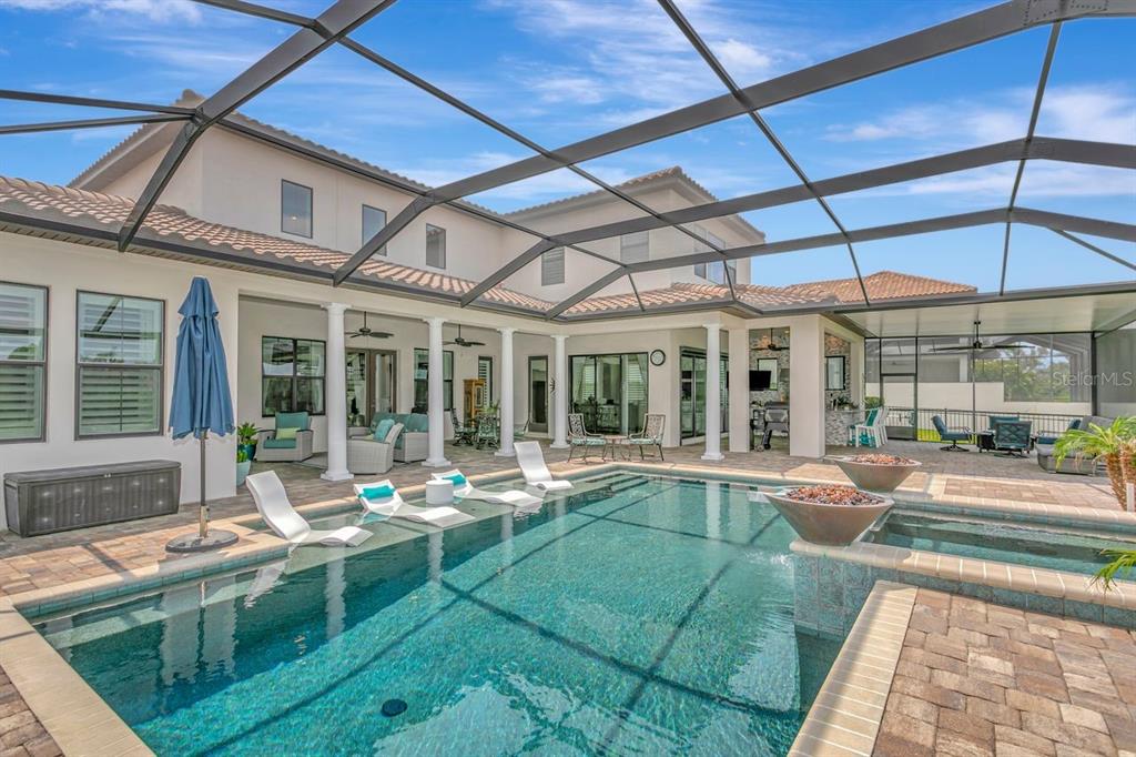 A screened-in patio features a swimming pool with lounge chairs and an outdoor kitchen area — 14922 FISHHAWK PRESERVE DRIVE, LITHIA, FL