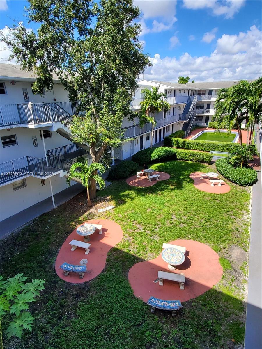 An elevated view of an apartment complex courtyard featuring a lawn, picnic tables, and pool — 13700 NE 6th Ave # 113, North Miami FL 33161, NORTH MIAMI, FL