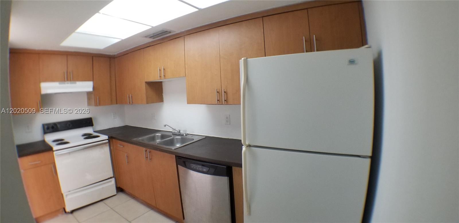 A kitchen features light wood cabinets, dark countertops, a white stove, and a white refrigerator — 13700 NE 6th Ave # 113, North Miami FL 33161, NORTH MIAMI, FL