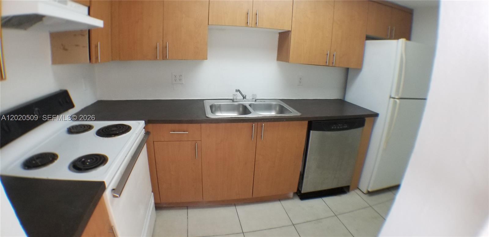 A kitchen features wood cabinets, dark countertops, a white stove, and a stainless steel dishwasher — 13700 NE 6th Ave # 113, North Miami FL 33161, NORTH MIAMI, FL