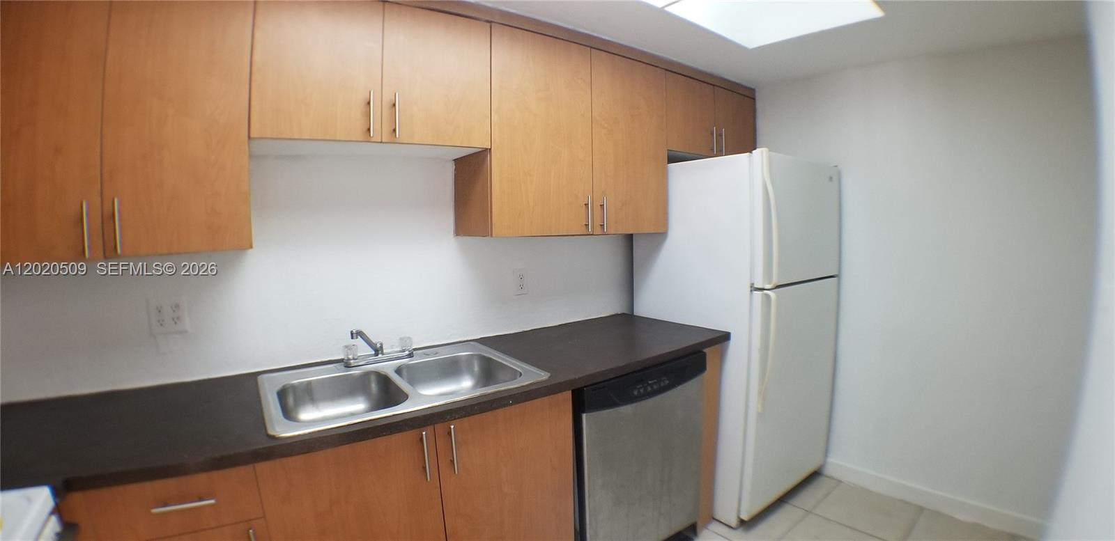 A kitchen features light wood cabinets, a dark countertop, a double sink, and white appliances — 13700 NE 6th Ave # 113, North Miami FL 33161, NORTH MIAMI, FL