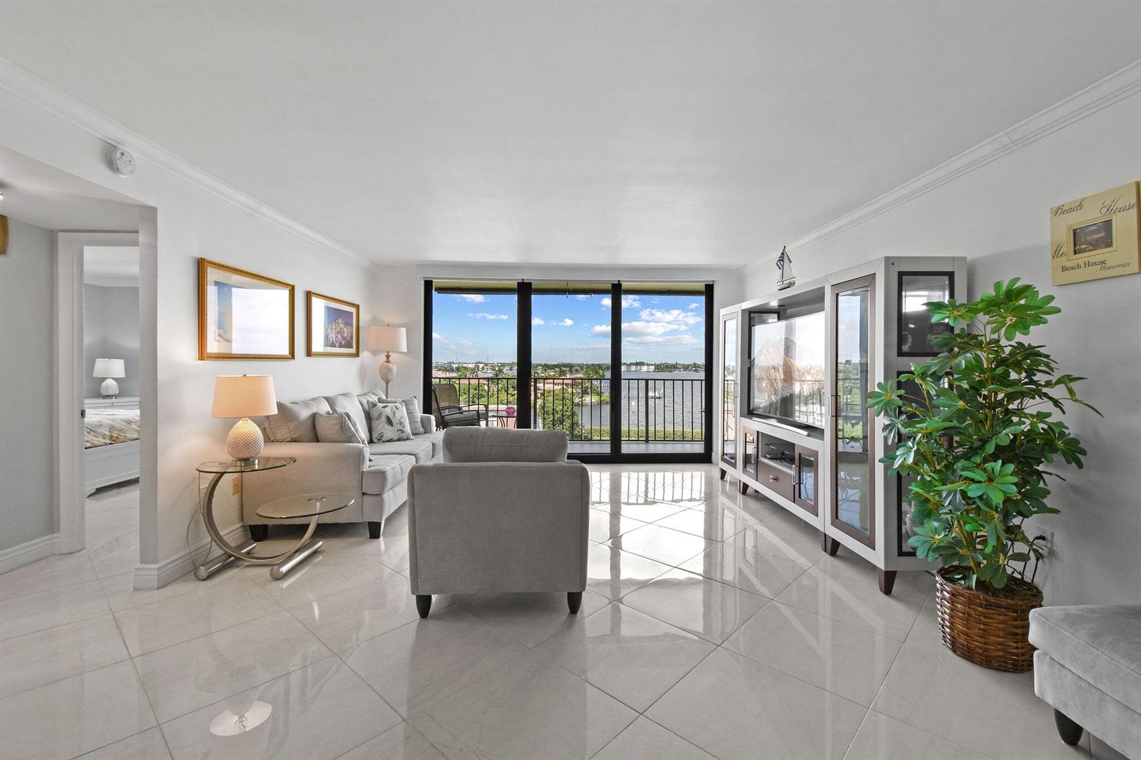 A bright living room features white tile floors, a sofa, an armchair, and a balcony view — 3460 S Ocean Boulevard # 510, Palm Beach FL 33480, PALM BEACH, FL