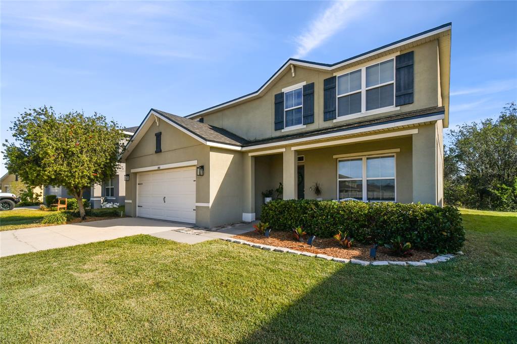 A two-story suburban house with a tan stucco exterior, a garage, and a front lawn — 3416 SAN MOISE PLACE, PLANT CITY, FL