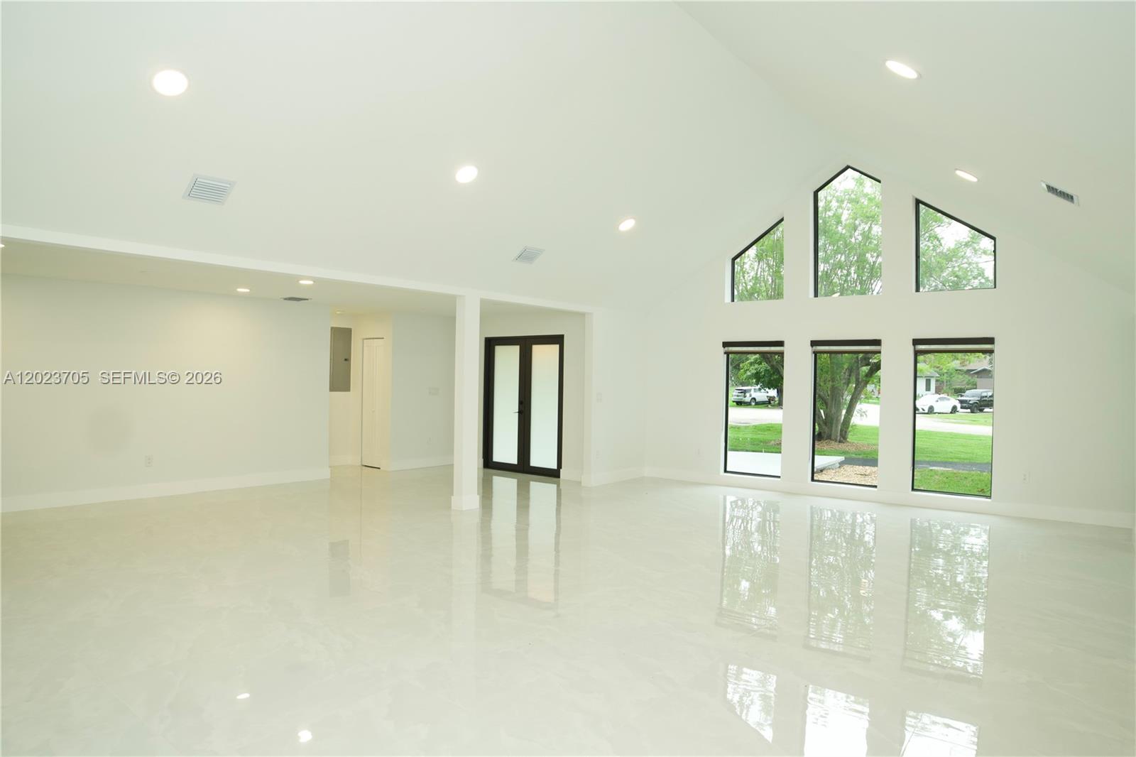 A bright, open living room features white walls, glossy tile floors, and large windows — 20500 SW 50th Pl, Southwest Ranches FL 33332, SOUTHWEST RANCHES, FL
