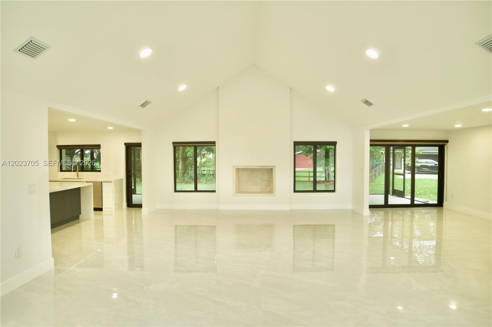 A spacious living room features a vaulted ceiling, white tile floors, and a central fireplace — 20500 SW 50th Pl, Southwest Ranches FL 33332, SOUTHWEST RANCHES, FL