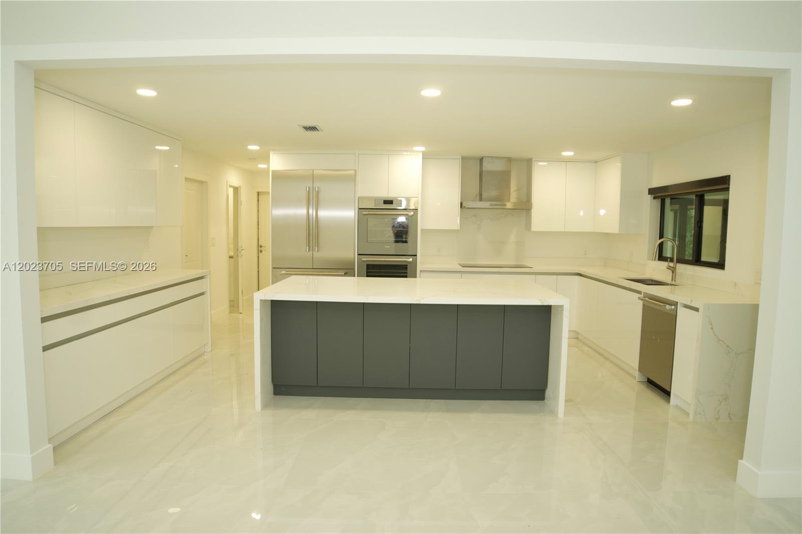 A modern kitchen features white cabinetry, a dark gray island, and stainless steel appliances — 20500 SW 50th Pl, Southwest Ranches FL 33332, SOUTHWEST RANCHES, FL