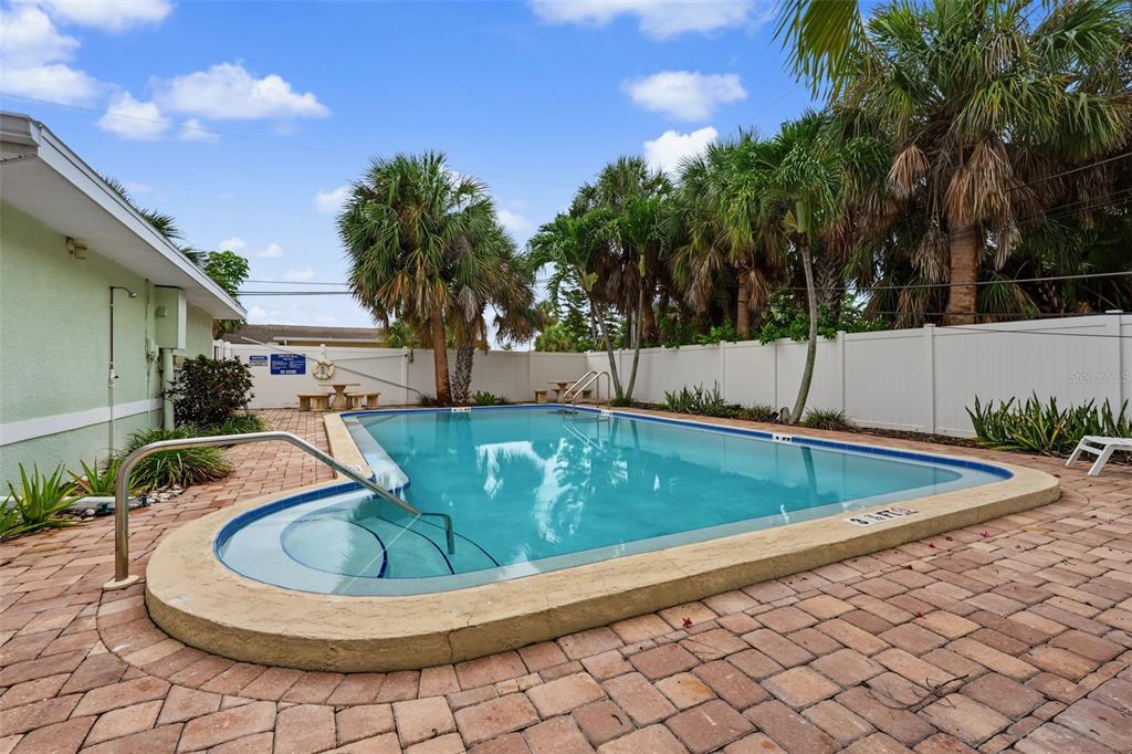 A rectangular swimming pool with a built-in step area sits on a brick patio — 9040 BLIND PASS ROAD UNIT A7, ST PETERSBURG, FL