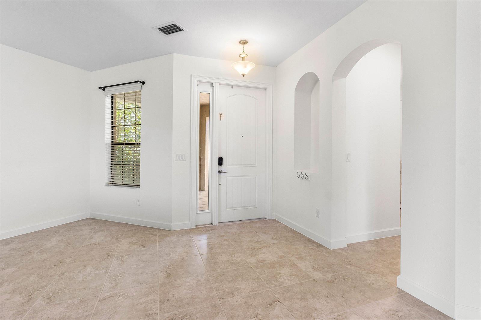An entryway with tile flooring, a white front door, and an arched wall niche — 5428 Sandbirch Way, Lake Worth FL 33463, LAKE WORTH, FL