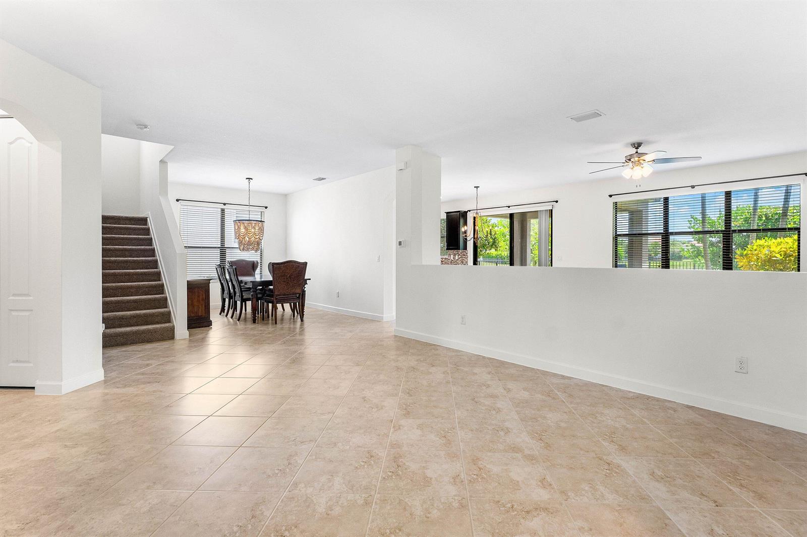 An open-concept living area features beige tile flooring, a carpeted staircase, and a dining space — 5428 Sandbirch Way, Lake Worth FL 33463, LAKE WORTH, FL