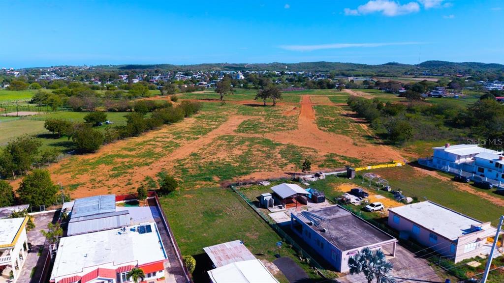 An aerial view shows a large, undeveloped dirt lot adjacent to several residential houses — Carretera 301 Km 0.6 COMBATE, CABO ROJO, PR