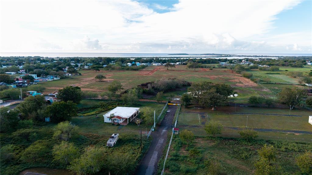 An aerial view shows a house, a driveway, and a large cleared field near water — Carretera 301 Km 0.6 COMBATE, CABO ROJO, PR