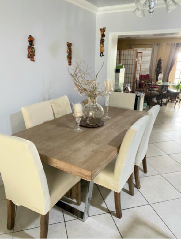 A dining room features a wooden table with cream-colored chairs and decorative wall art — 2441 PINE TREE Drive, Miramar FL 33023, MIRAMAR, FL