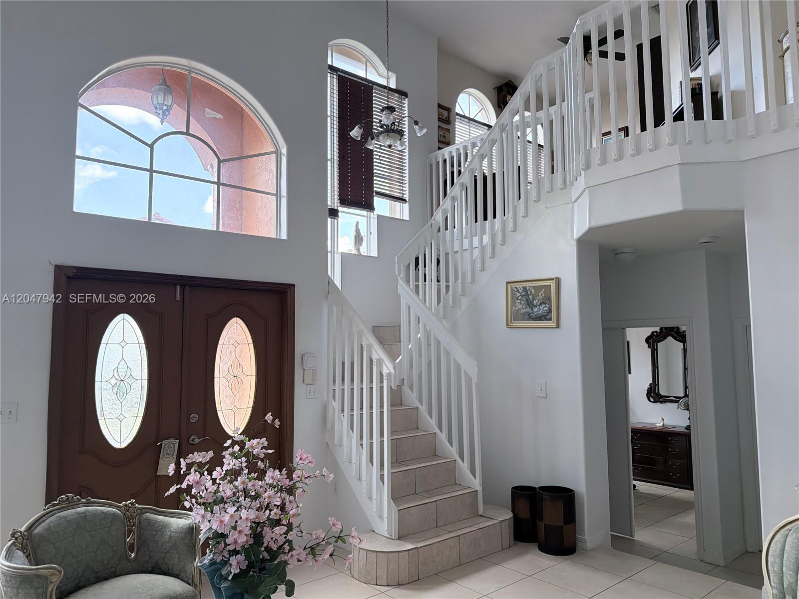 A high-ceilinged foyer features a tiled staircase, arched windows, and a double front door — 10824 NW 51st Ln, Doral FL 33178, DORAL, FL