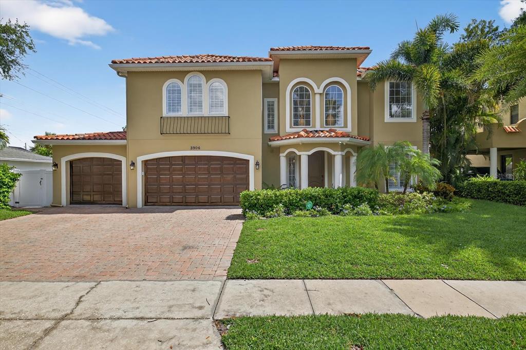 A two-story house with a tan stucco exterior, tile roof, and a three-car garage — 3904 W SANTIAGO STREET, TAMPA, FL
