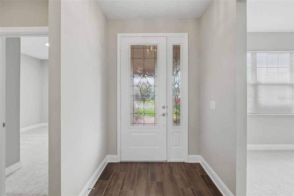 A foyer with wood-look tile flooring, light gray walls, and a white front door — 251 TEDDY RUSHING STREET, DEBARY, FL