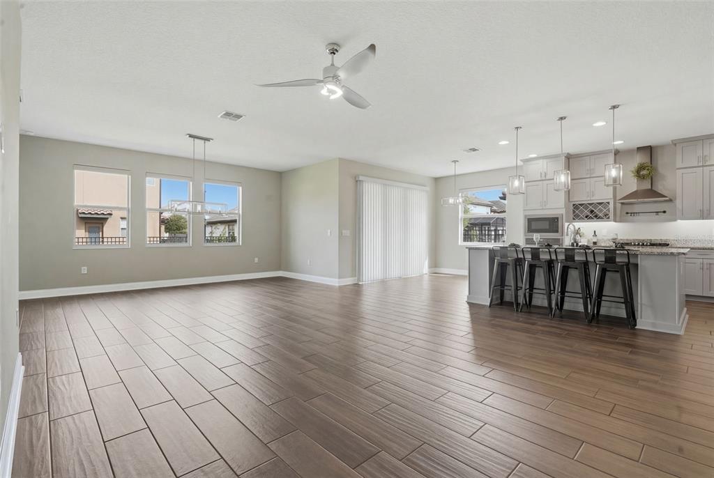An open-concept kitchen and living area features wood-look tile flooring and a large island — 251 TEDDY RUSHING STREET, DEBARY, FL